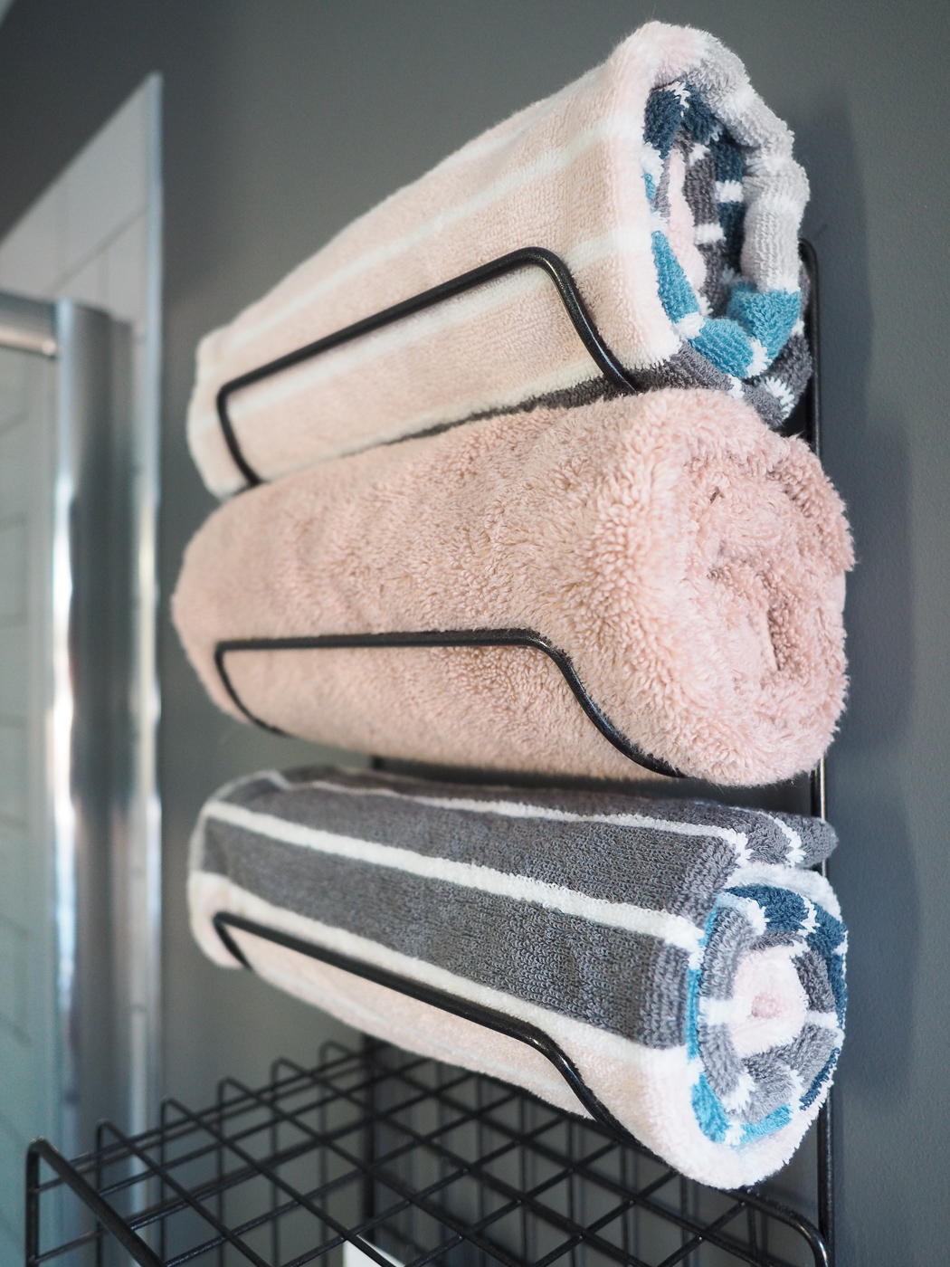 pink and grey and teal towels in a towel rack